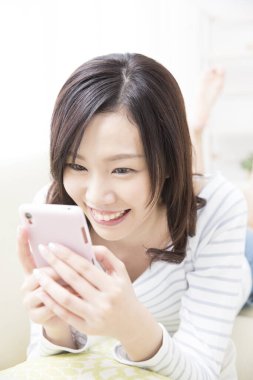 Güzel Asyalı kadın evde akıllı telefon kullanıyor.