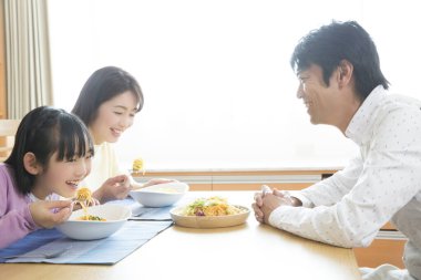 Asyalı aile evde öğle yemeği yiyor. 