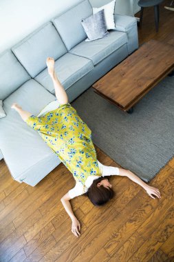 Kanepeden düşen Asyalı genç kadın. 