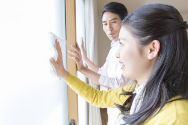 Beyaz elbiseli genç çift pencereyi temizliyor.