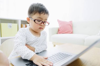 Genç Asyalı çocuk evde akıllı laptop kullanıyor.