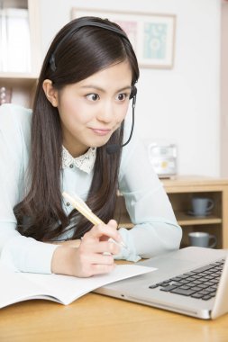 Kulaklıklı Asyalı kadının portresi dizüstü bilgisayarda ders alıyor. 