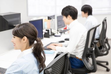 Ofisteki bilgisayarlarda çalışan genç iş adamları