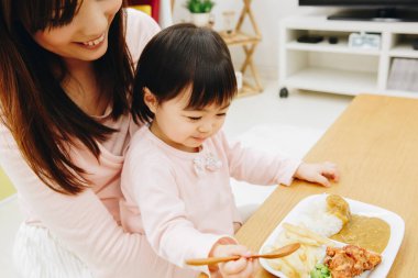 Asyalı bir aile mutfakta yemek yiyor.