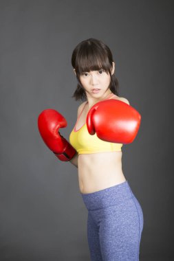 Asyalı kadın boks eldiveni giyiyor.