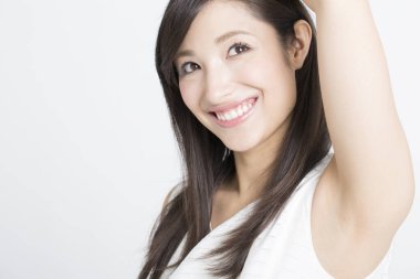 Genç Asyalı kadın gülümsüyor ve koltuk altını gösteriyor.