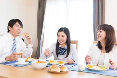 Üç kişilik Japon ailesi mutfakta kahvaltı yapıyor.