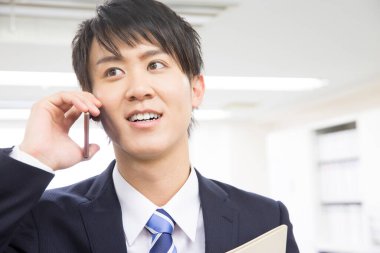 İş adamı ofiste cep telefonuyla konuşuyor. 