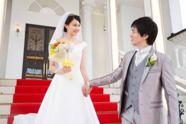 Merdivenlerde poz veren mutlu Asyalı gelin ve damadın portresi.