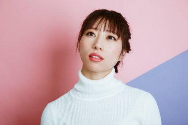 Beyaz kazaklı genç Asyalı kadın portresi, stüdyo fotoğrafı. 