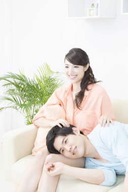 Genç Asyalı çift evdeki kanepede dinleniyor.