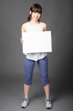 Genç Japon kadın elinde beyaz bir tabela tutuyor.