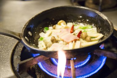 Şef mutfakta tavayla yemek pişiriyor. 