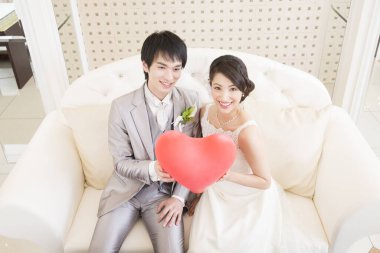 Güzel, mutlu, genç bir çift kırmızı kalple poz veriyor.