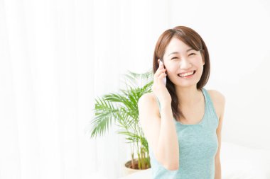 Asyalı kadın evde akıllı telefon kullanıyor.