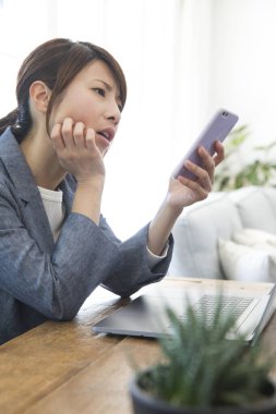 İş kadını iş yerinde akıllı telefon kullanıyor.