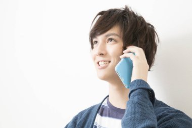 Asyalı genç adam cep telefonuyla konuşuyor.