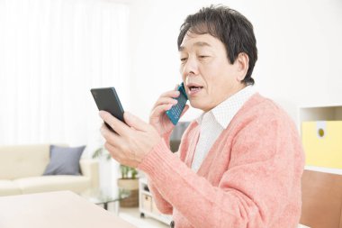 Usta Asyalı adam cep telefonu ve akıllı telefon kullanıyor. 