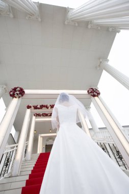 Sütunların altında kırmızı halılı merdivenler yükselen gelin