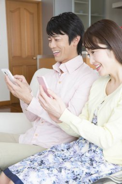 Genç çift evde akıllı cep telefonları kullanıyor. 