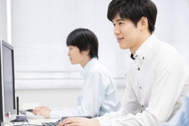 Bilgisayarlarda çalışan Asyalı genç erkek öğrenciler