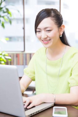 Asyalı kadın dizüstü bilgisayar kullanıyor.