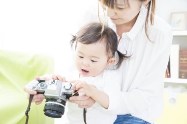Kadının biri bebeğin klasik kamerayı tutmasına yardım ediyor.