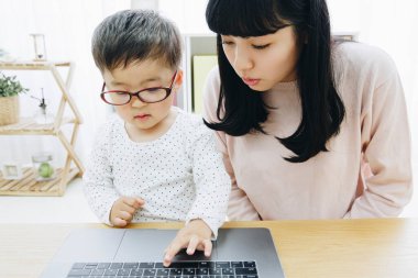 Asyalı anne ve oğlu dizüstü bilgisayar kullanıyor.