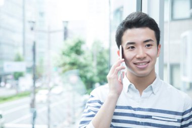 Genç adam ofiste akıllı telefon kullanıyor.