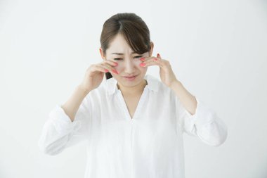 Beyaz arka planda ağlayan güzel üzgün Japon kadının stüdyo çekimi. 