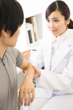 Doktor erkek hastaya iğne yapıyor. 