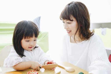 Evdeki oturma odasında annesiyle oynayan tatlı Asyalı küçük kız.