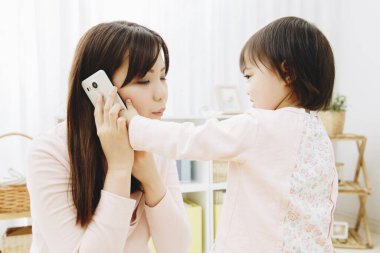 Anne oturma odasında akıllı telefonla kızını oynuyor..