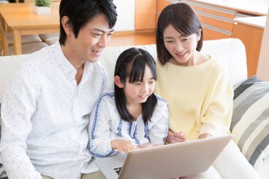 Kızı evde dizüstü bilgisayar kullanan Asyalı genç bir çift.