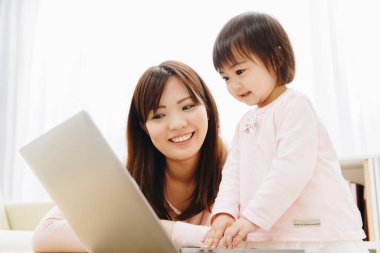 Güzel Asyalı anne ve kızını dizüstü bilgisayarla kapat.