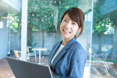 Modern ofiste dizüstü bilgisayar kullanan güzel bir Japon iş kadını.