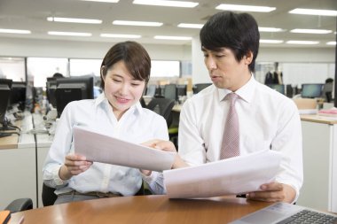 İki genç iş adamı ofiste belgeleri tartışıyor ve inceliyor. 