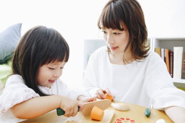 Evdeki oturma odasında annesiyle oynayan tatlı Asyalı küçük kız.