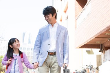 Asyalı baba ve kızı sokakta birlikte yürüyorlar.