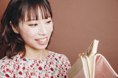 Asyalı kadın para ve cüzdan tutuyor.