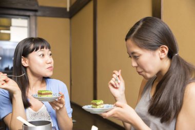 Masada tatlı yiyen iki kadın.