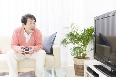 Genç Çinli adam oturma odasında oyun oynuyor.