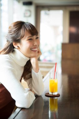 Restoranda portakal suyu içen Asyalı kadın.