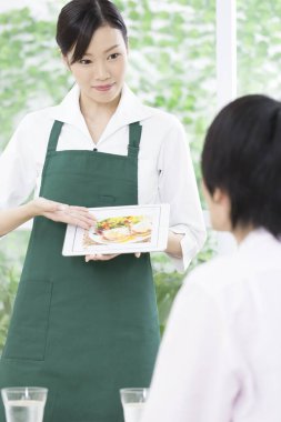 Asyalı garson restorandaki tablette menüyü gösteriyor