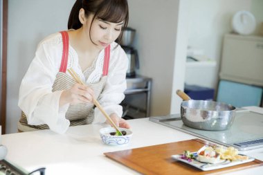 Güzel Asyalı kadın mutfakta yemek yapıyor.