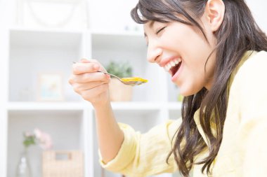 Gülümseyen genç Japon kadın evde jöle yiyor.