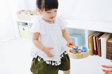 Küçük tatlı Japon kız oturma odasında oyuncaklarla oynuyor.