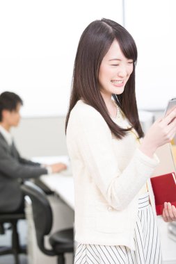 Ofisteki akıllı telefonlu genç iş kadını. 