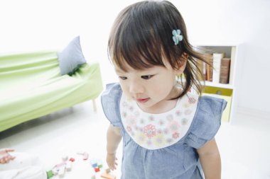 Evdeki oturma odasında oynayan tatlı Asyalı küçük kız.