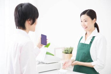 Akıllı telefonlu bir adam dükkanda online ödeme yapıyor. 